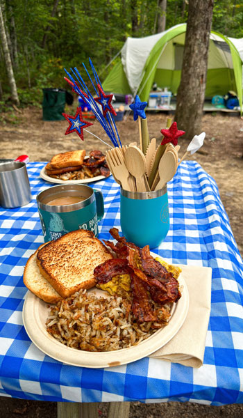 camping table loaded with bamboo dinnerware and a meal